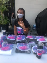 a girl with a face mask sitting at a table with t - shirts