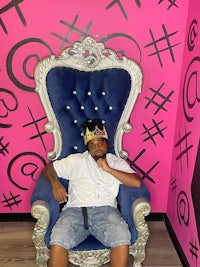 a man sitting on a blue chair in a pink room